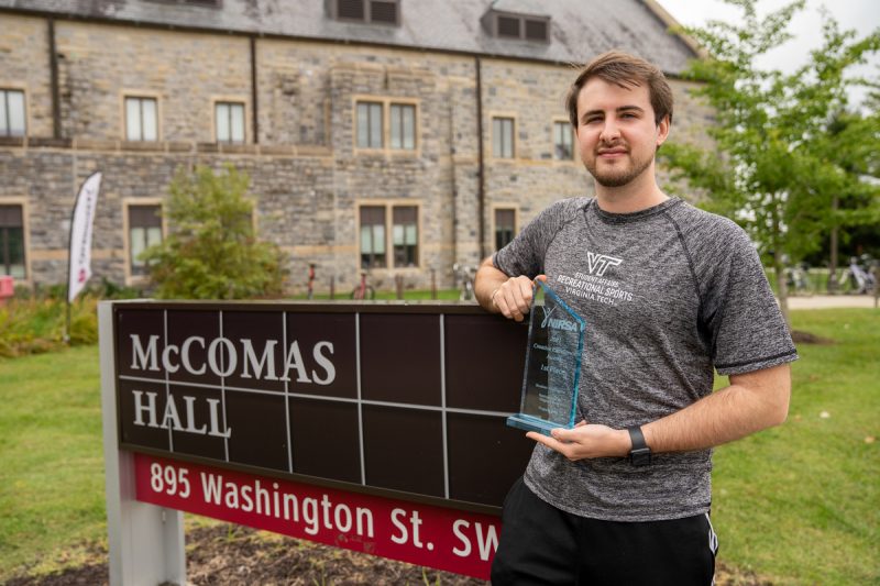Ethan posing in front of mccomas hallsign